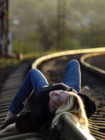 Young blond woman in casual dress lying on railの写真素材