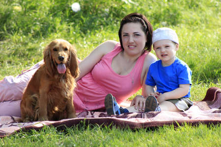 Yong mother with toddler and dog sitting on rad on natureの写真素材