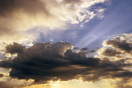 Dramatic cumulus clouds with sunbeams before rain