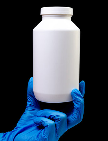 Medical pills in white jar on an isolated black background with reflection in hand natural organic...