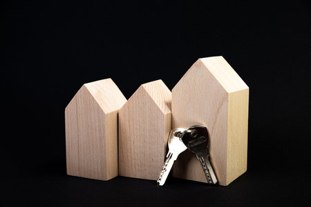 Houses symbol with metal key on black background. Real estate, insurance concept, buy sell house, realtor concept. Isolated, wooden houses, new life. housewarming, lock and keychain little carsの写真素材