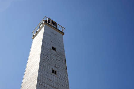 Old wooden lighthouse under blue sky.の写真素材