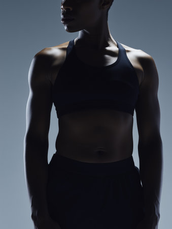 Silhouette of a strong sporty African American woman in black sportswear during a workout. Concept of a healthy lifestyle.の素材