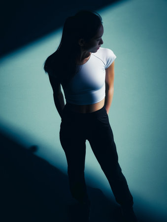 Silhouette of a sporty Asian woman on a blue background with shadows.の素材