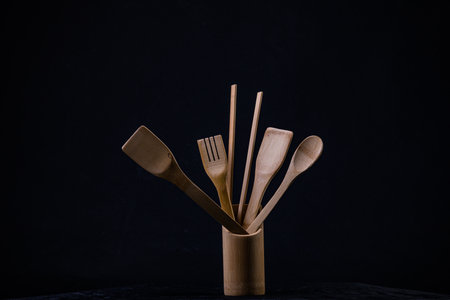 Wooden kitchen utensils on a dark background. Zero waste concept.