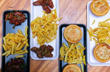 French fries and tartlets with dried tomatoes on a wooden table.
