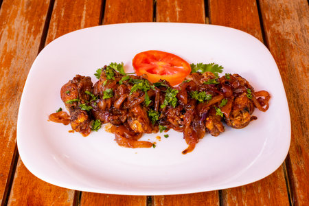 Fried pork with sweet and sour sauce on a white plate on a wooden tableの写真素材