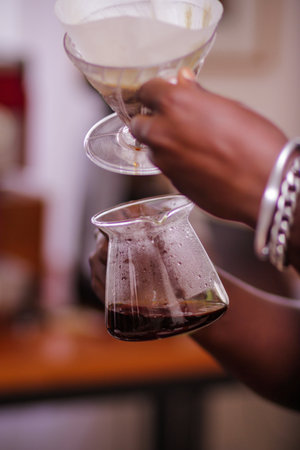 Close-up of barista pouring coffee in a glass cup.の写真素材