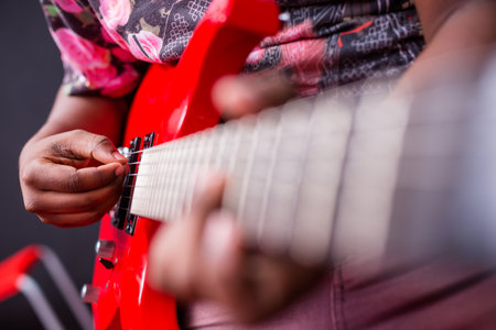 Close-up of a man playing on a red electric guitar.