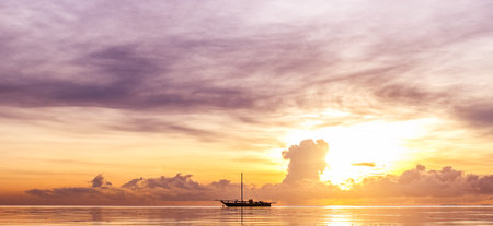 Panoramic view of a sailboat in the sea at sunset
