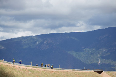 Group of people running on the road in the mountains under cloudy skyの写真素材