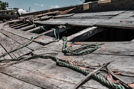 Old wooden boat with green rope on the beach, close up.の写真素材