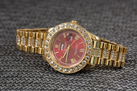 Luxury gold wrist watch on grey textured background closeup