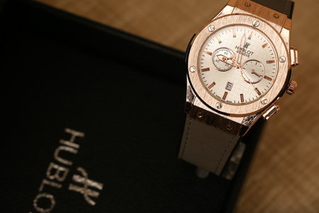 Wristwatch with black leather case on wooden background. Selective focus.