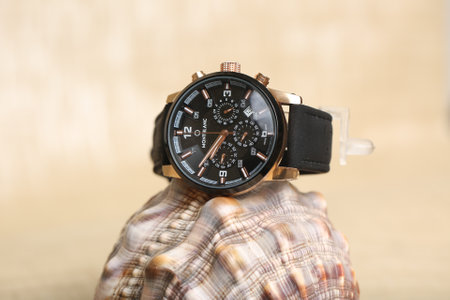 Wristwatch with black dial and brown leather strap on wooden background