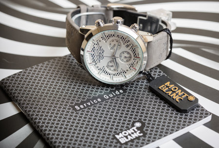 Wristwatch and passport on a black and white striped background.