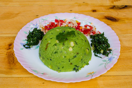 Rice cake with green sauce on a plate on a wooden table