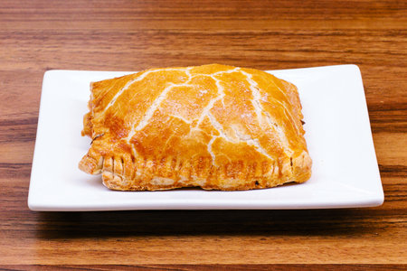 Apple strudel on a white square plate on a wooden table
