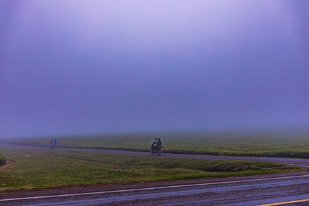 Cyclists riding on the road with fog in the background.の写真素材
