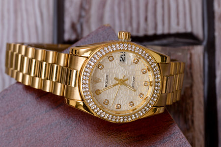 Wrist watch with a gold dial and diamonds on a wooden backgroundの写真素材