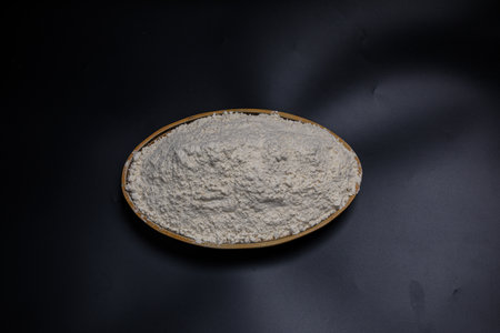 Heap of wheat flour in a plate on a black background.の写真素材