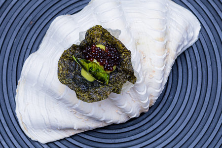 Seafood tartare with avocado and caviar on a black background