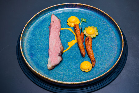 Tuna steak with egg yolk and carrot on blue plate.の写真素材