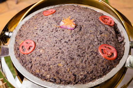 Close up of delicious black rice cake with red onion and tomato.