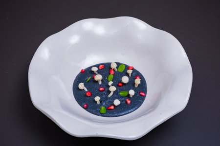 Black pudding with pomegranate seeds on a white plate.の写真素材