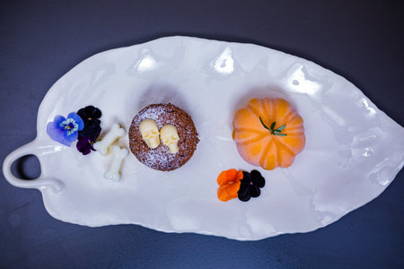 Cupcake with pumpkin and pansy flowers on a white plateの写真素材