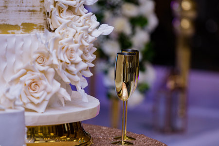Wedding cake with white roses and champagne glasses on the tableの写真素材