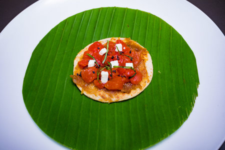 Crispbread with tomato, mozzarella cheese and herbs on banana leaf