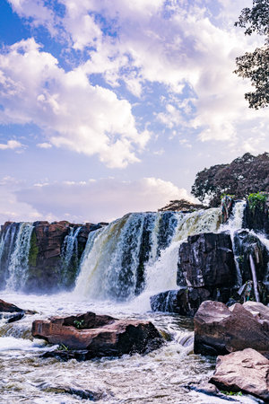 Waterfall in thailand with blue sky and white cloud background.