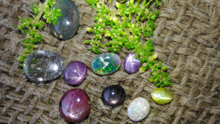 Precious gemstones including star ruby, star sapphire , cat's eye and opal are placed on a Jute...