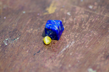 Closeup view of gemstones including lapis lazuli and cats eye kept on a wooden plank