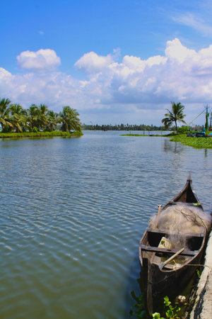 View from the bangs of a river with a small fishing boat in the foregroundの写真素材