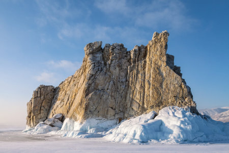 Figured rock surrounded by ice on blue sky background