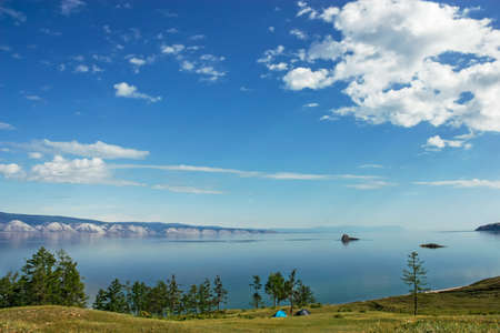 Two tents on the coast of beautiful lake surrounded by mountainsの写真素材