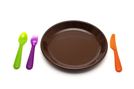 colored cutlery and a plate on white background