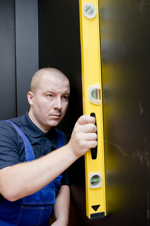 Man using a yellow spirit level on black wallの写真素材