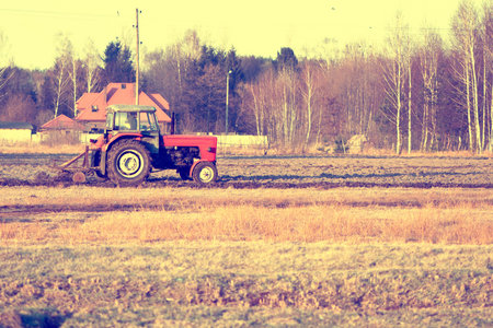 view of the old tractor plowing the fieldの写真素材