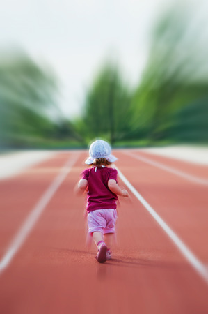 little girl runs across the trackの写真素材