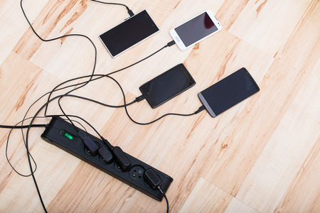 four smartphones connected to chargersの写真素材