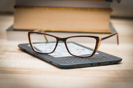 The glasses are lying on the book reader. Traditional books in the backgroundの写真素材