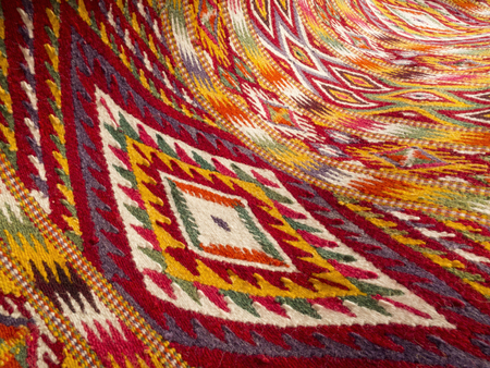 Close up of a hanged colourful handmade traditional rug - woven with white, black, yellow, red and green wool - abstract backgroundの写真素材