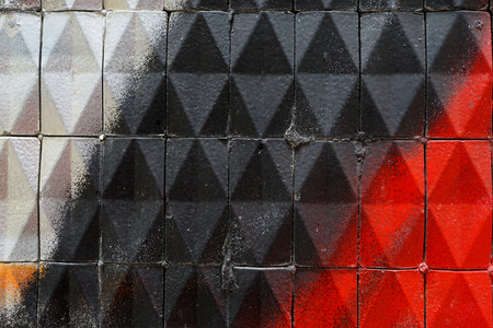 Dirty old facade with ceramic triangular tiles - painted with 
white, black, red, orange paintの写真素材