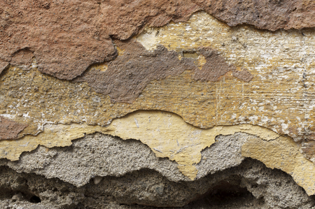 Close up of old, crumbling,cracked, grunge red-brick wall with mortar cement. 
Several different layers of peeled  orange, beige, brown,grey,yellowish-brown and ocher facade  paint.  Detail abstract texture background with space for  text, copy, your wordの写真素材