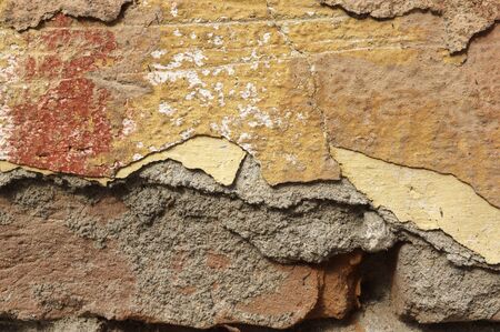 Close up of old, crumbling,cracked, grunge red-brick wall with mortar cement. 
Several different layers of peeled  orange, beige, brown,grey,yellowish-brown and ocher facade  paint.  Detail abstract texture background with space for  text, copy, your wordの写真素材
