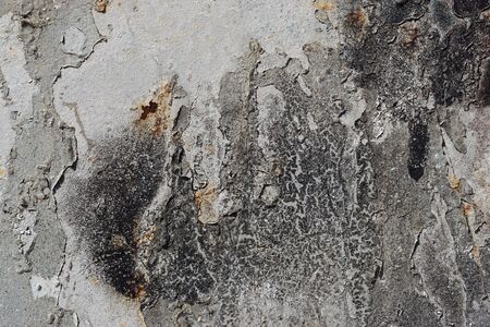 Abstract textured background. Grunge metal close up.Rusty, dirty old metal sprinkled with black, grey and silver paint.Colorful, scratched, cracked and peeled layers. Macro. の写真素材