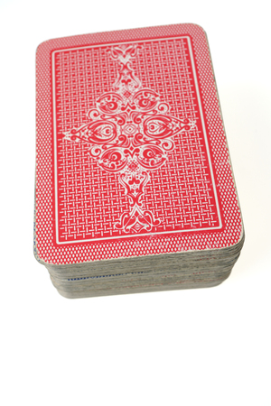 Stacked pile of old red cards - face down.
Standard  French deck of 52 playing cards.
Isolated on white background.の写真素材